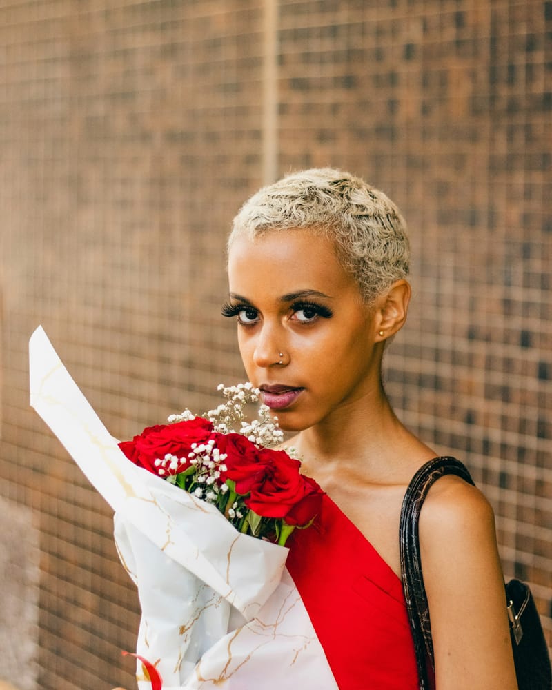A woman in a red dress holding a bouquet of flowers.